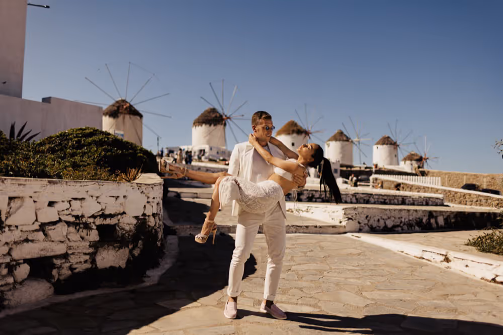 Ślub w Grecji. Mykonos. Pan młody trzyma na rękach swoją żonę.